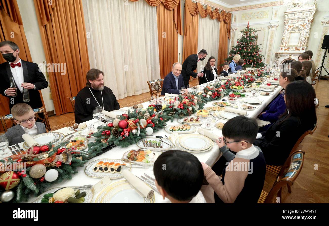 Novo-Ogaryovo, Russia. 07th Jan, 2024. Russian President Vladimir Putin, center, and Archbishop Nikolay Mosolov, left, host a dinner with military families following Orthodox Christmas celebrations at the official presidential compound, January 7, 2024 in Novo-Ogaryovo, Moscow Oblast, Russia. Putin hosted families of soldiers killed in the Ukraine war for the celebration. Credit: Gavriil Grigorov/Kremlin Pool/Alamy Live News Stock Photo