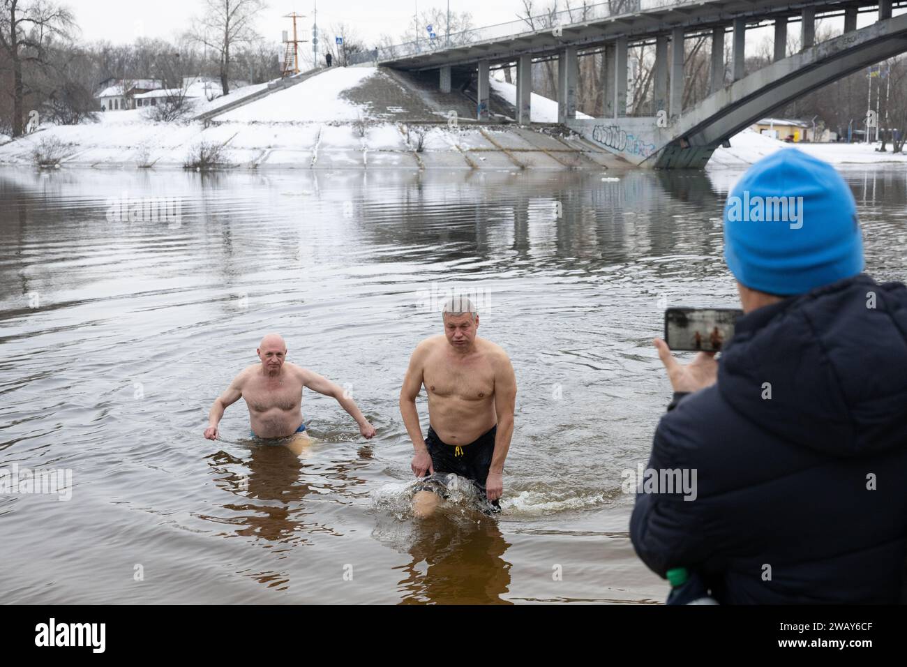 People come out of the water after swimming in cold Dnipro River on the occasion of the celebration of Epiphany in Kyiv. Ukraine celebrates Epiphany on January 6 for the first time this year, following the Western calendar, departing from the Russian Orthodox Church tradition of celebrating it on January 19. During Epiphany, some people believe that the waters have special curative properties and can be used to treat various illnesses, and many of them take baths in the water as part of Epiphany celebration. (Photo by Oleksii Chumachenko/SOPA Images/Sipa USA) Stock Photo