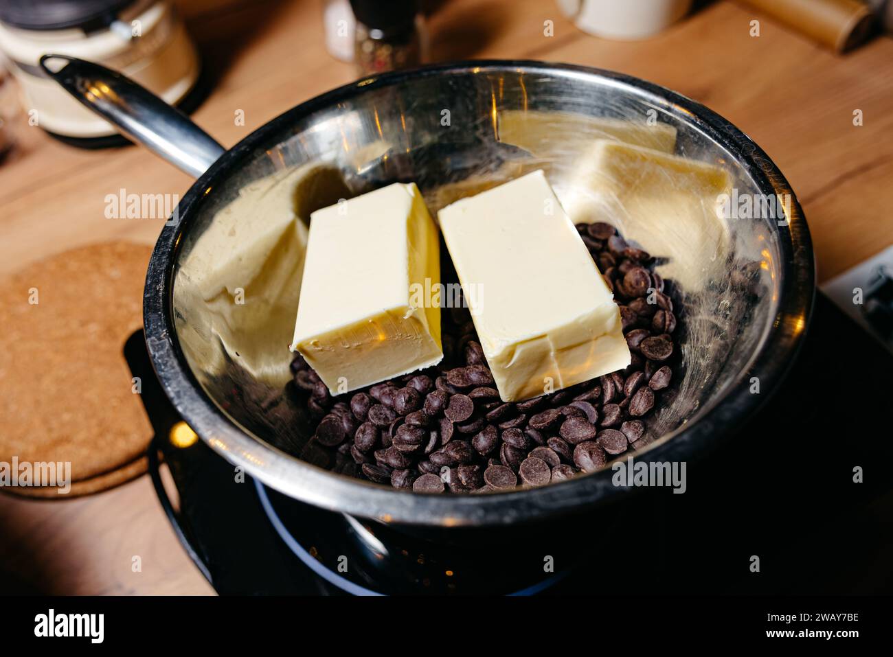 A double boiler pan with dark chocolate chips and blocks of butter, a classic technique for melting ingredients smoothly for baking. Stock Photo