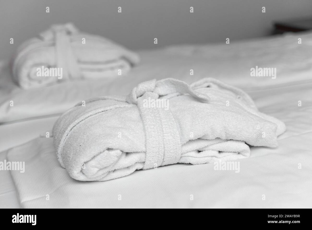Bavaria, Germany - January 5, 2024: White bathrobe on the bed of a hotel room *** Weißer Bademantel auf dem Bett von einem Hotelzimmer Stock Photo