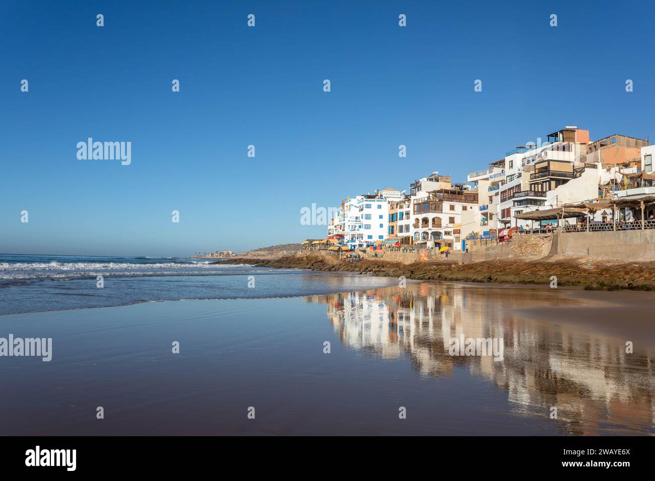 Beach front houses / cafes overlooking the Atlantic Ocean and beaches in the fishing village of Taghazout, Morocco, North Africa on a sunny day Stock Photo