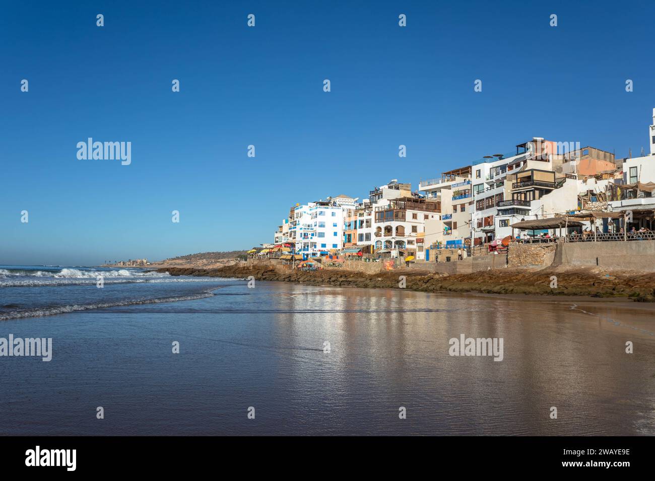 Beach front houses / cafes overlooking the Atlantic Ocean and beaches in the fishing village of Taghazout, Morocco, North Africa on a sunny day Stock Photo