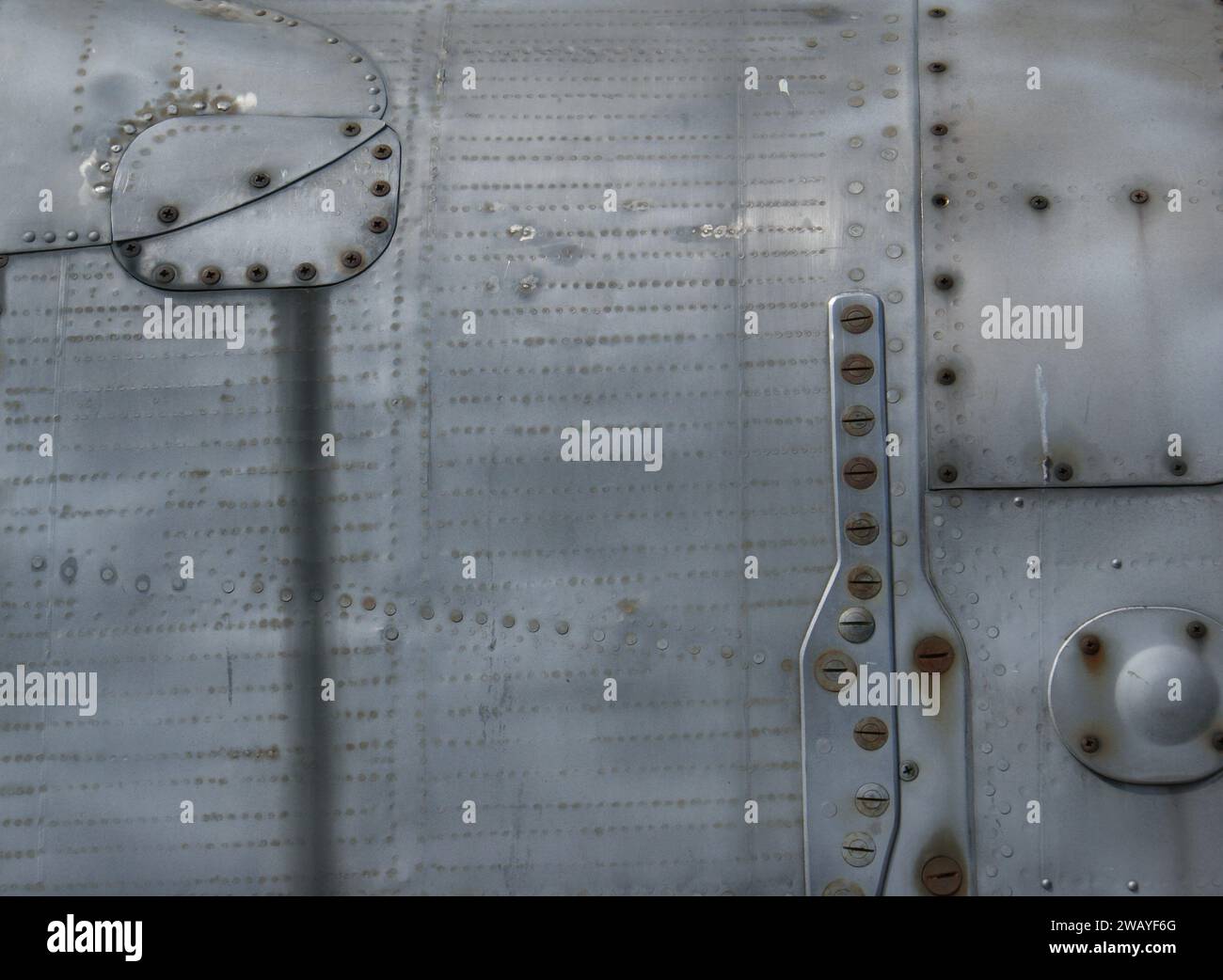 Fragment of an old metal fuselage. Metallic background with screws and rivets. Stock Photo