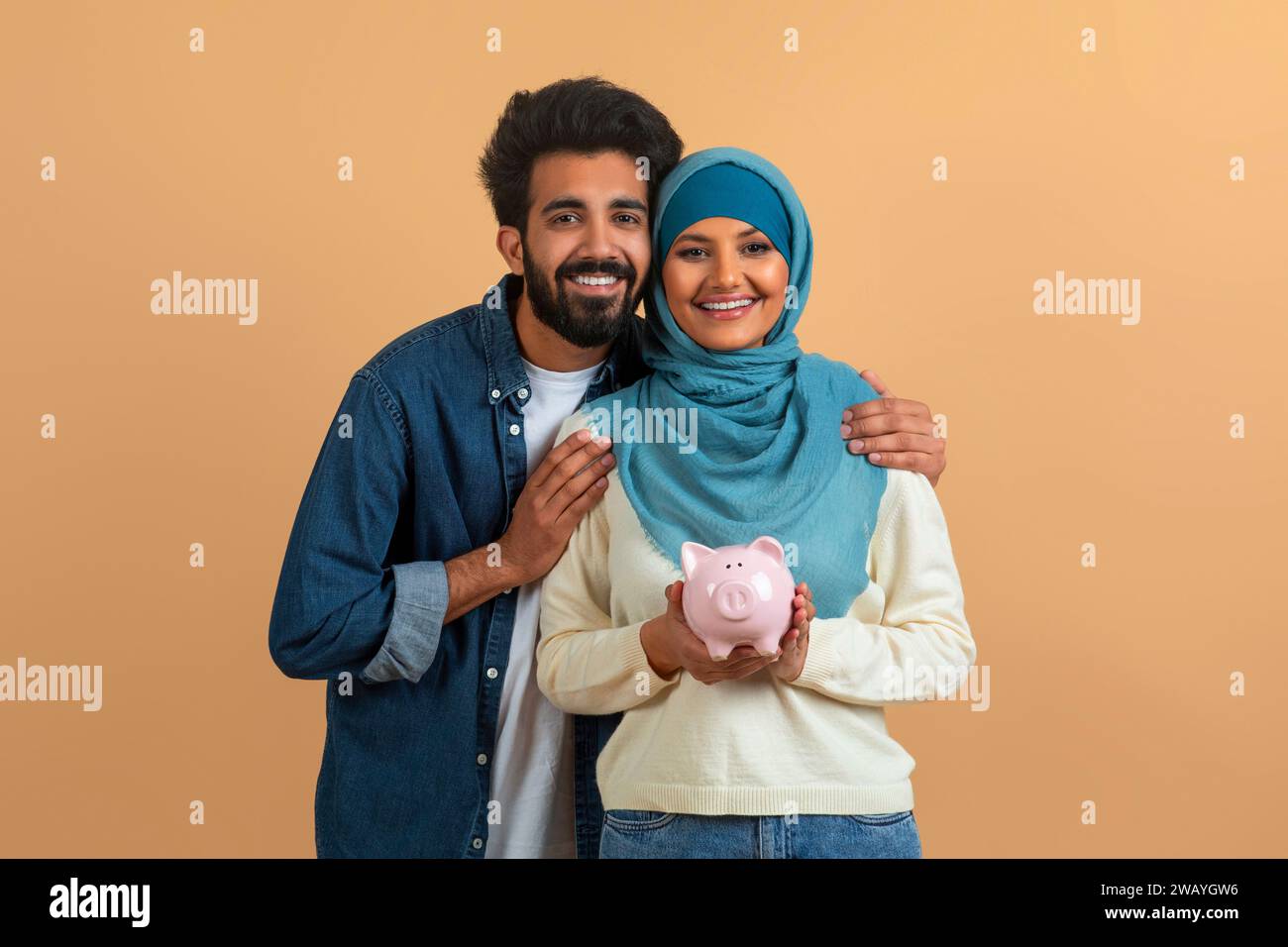 Happy muslim couple embracing and holding piggy bank Stock Photo - Alamy