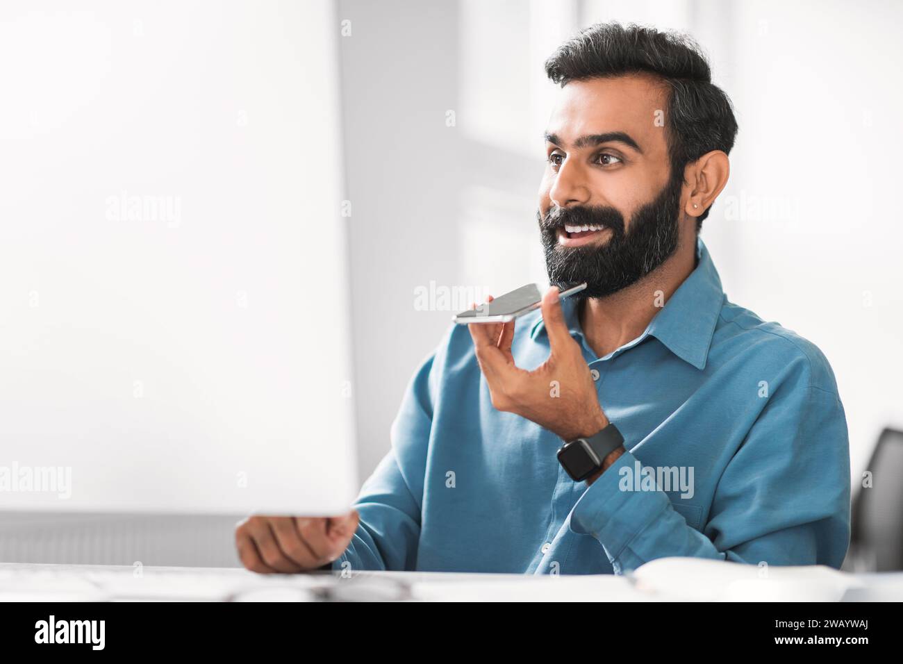 Businessman talking on speakerphone at his desk Stock Photo