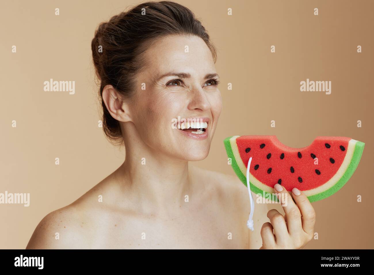 happy modern woman with watermelon shower sponge on beige background. Stock Photo