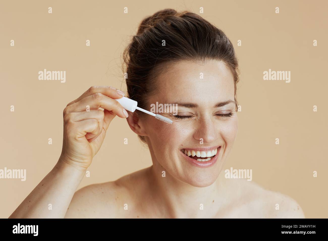 middle aged woman with brow brush isolated on beige background. Stock Photo