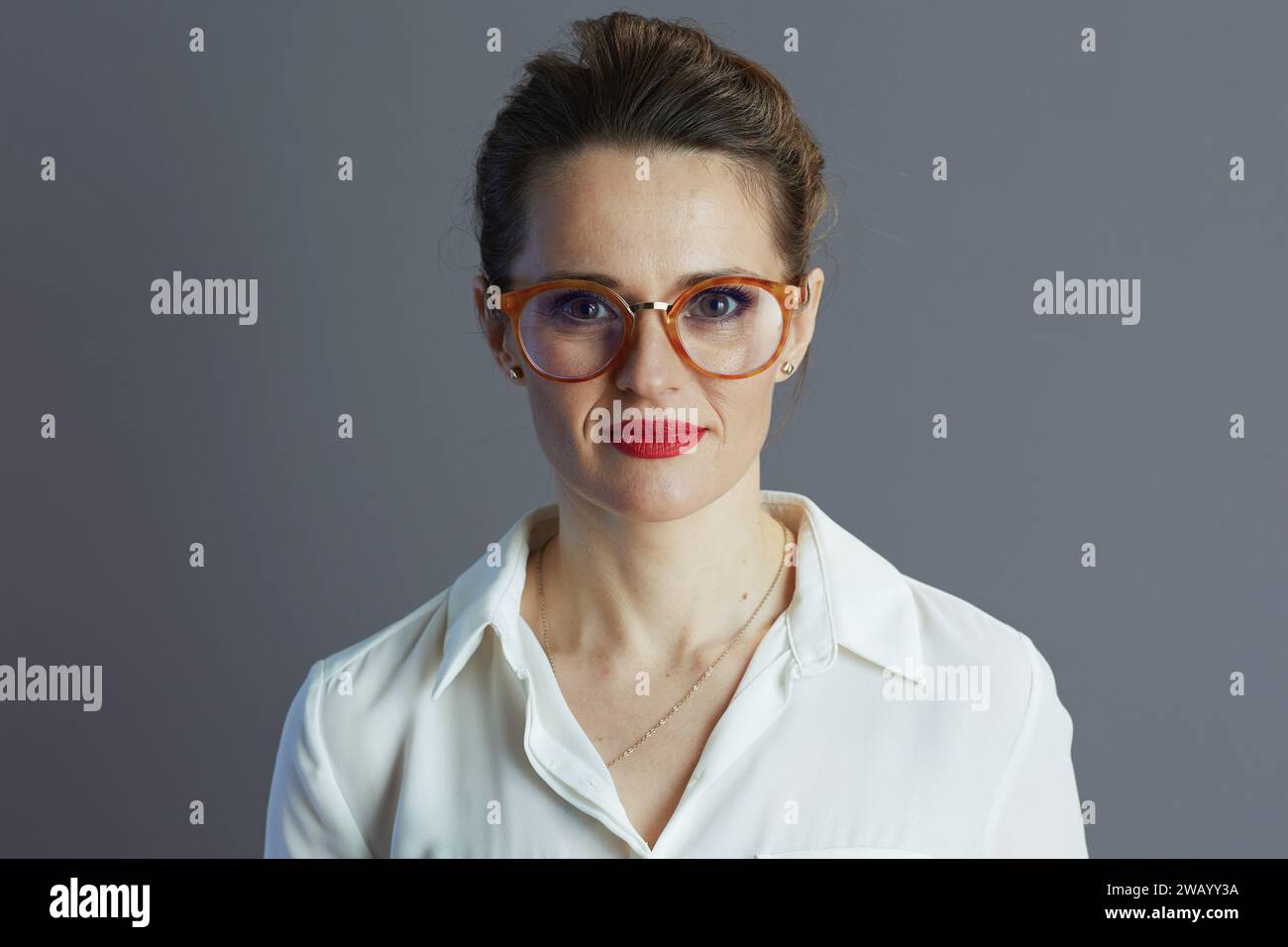 stylish middle aged small business owner woman in white blouse with glasses isolated on grey. Stock Photo