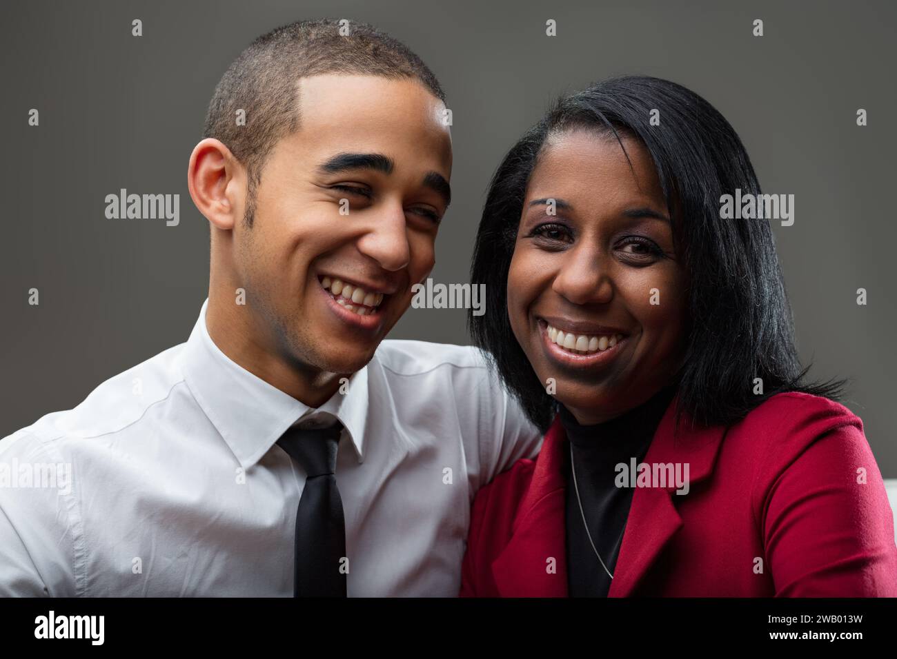 Side by side, the young gentleman's restrained smile complements the woman's exuberant laughter perfectly Stock Photo