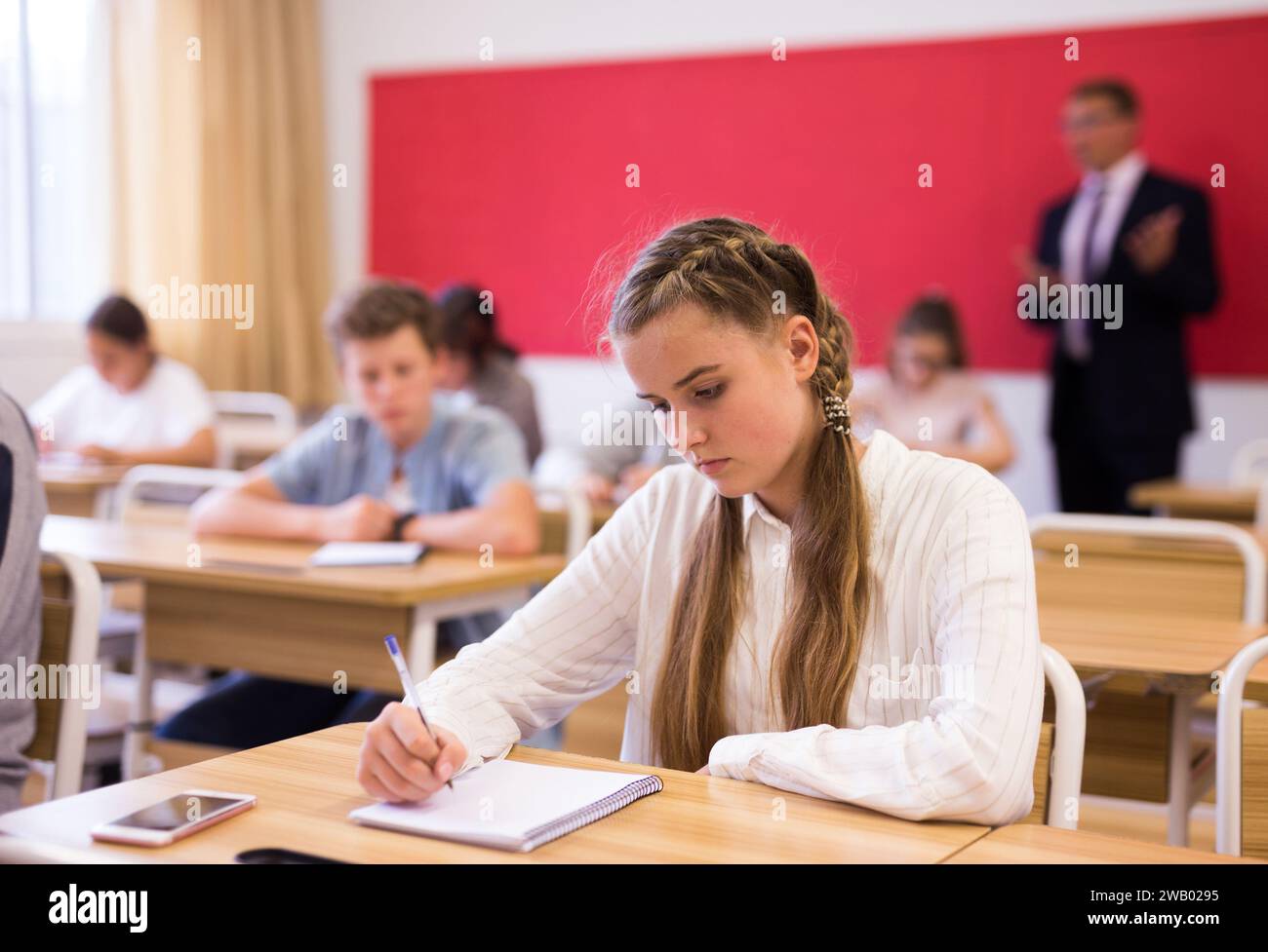 Teen girl sitting at desk in classroom Stock Photo - Alamy
