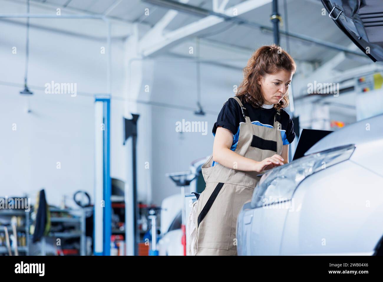 Technician in car service uses laptop to calculate invoice for client ...