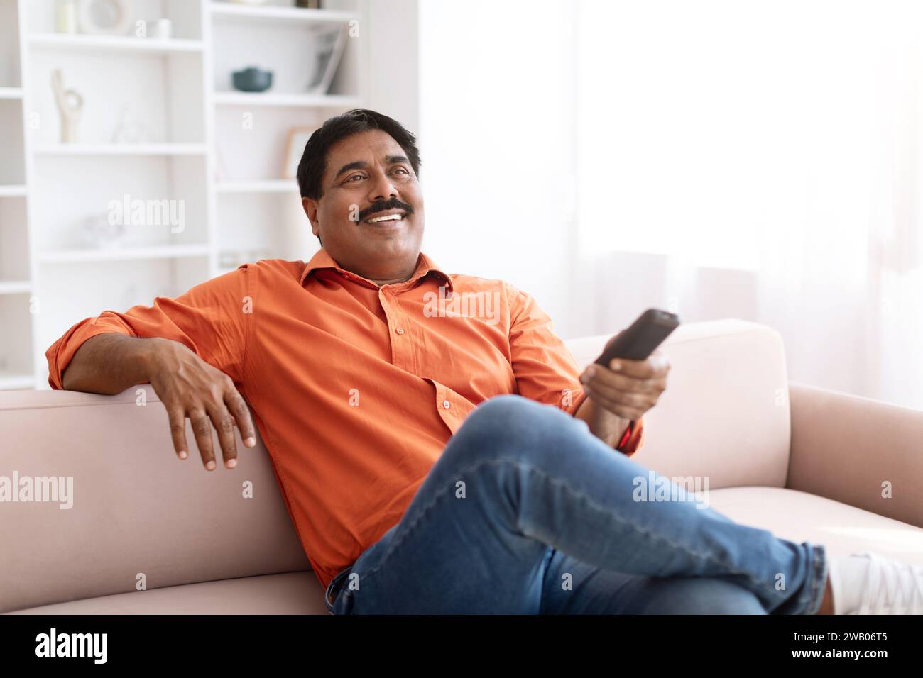 Happy mature indian man watching TV at home Stock Photo