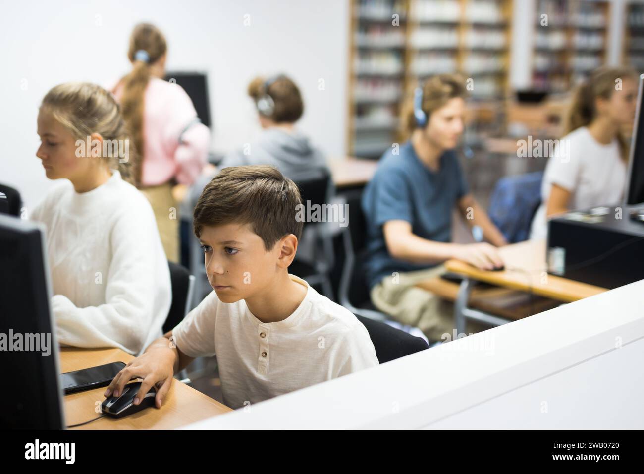 Preteen boy and girl learn to solve problems on computer in school ...