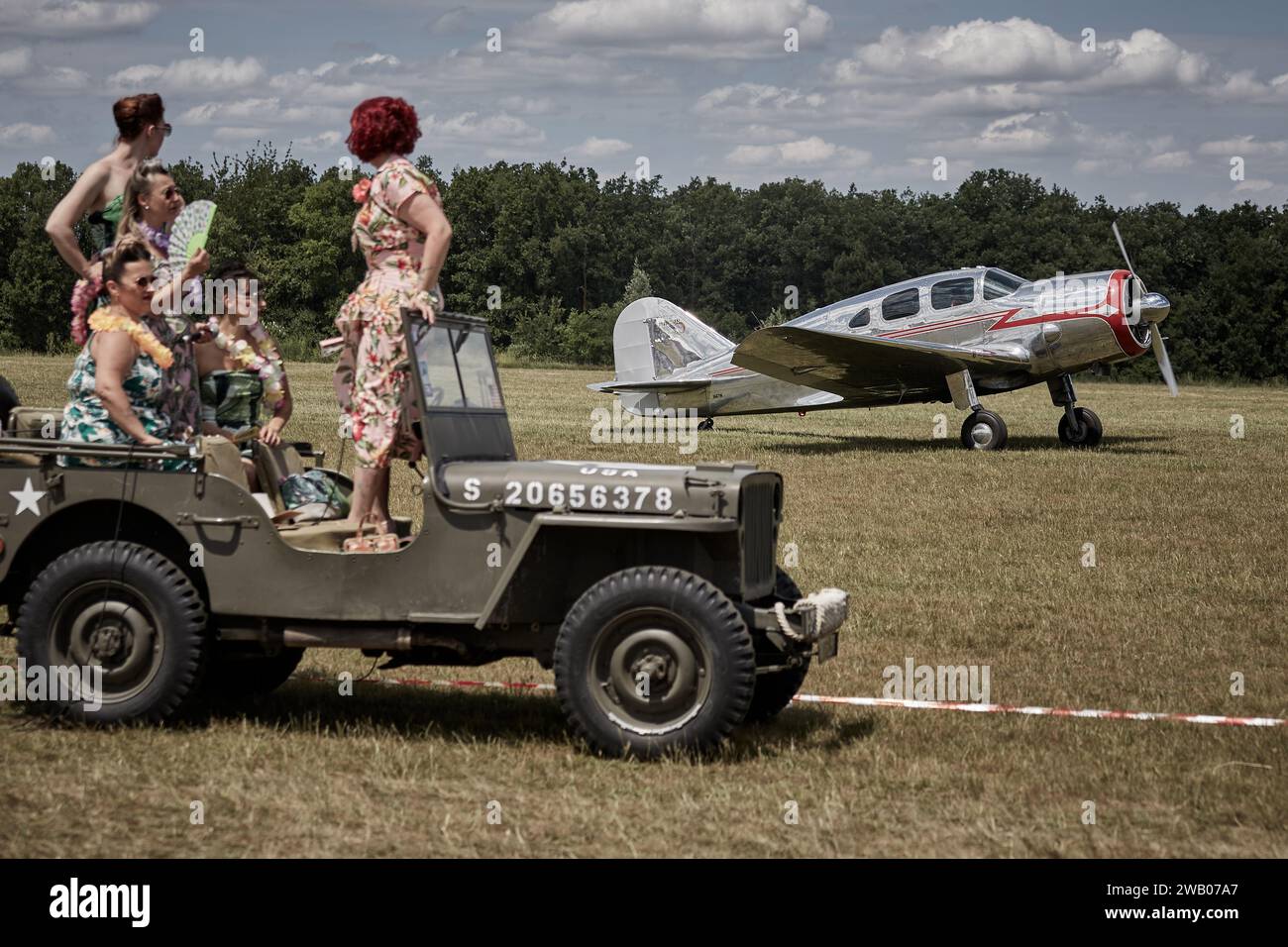 Pin-ups standing on a jeep Willys looking at Spartan Executive 7 W ready to take-off Stock Photo