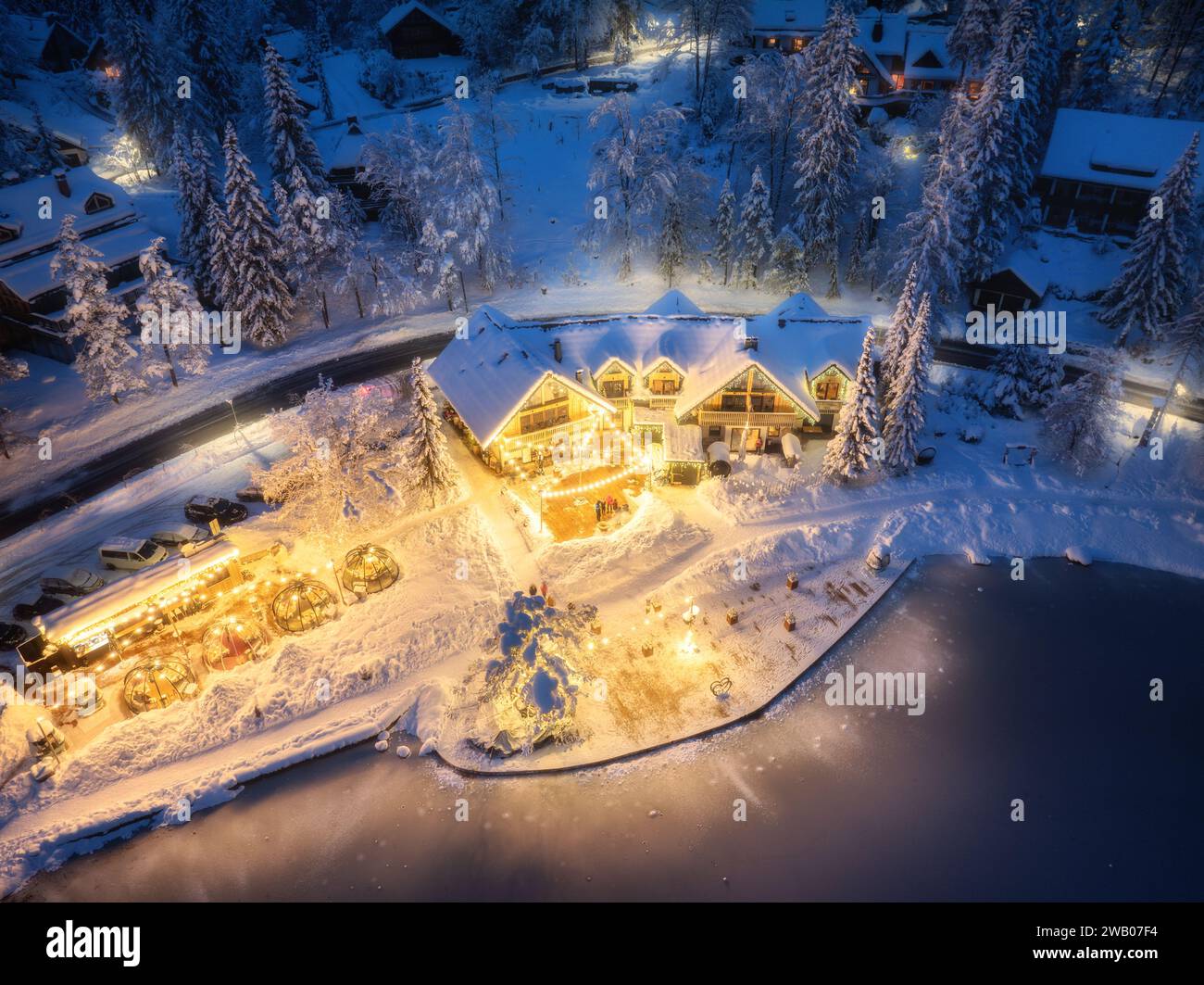 Aerial view of illuminated houses in snowy village at night Stock Photo ...
