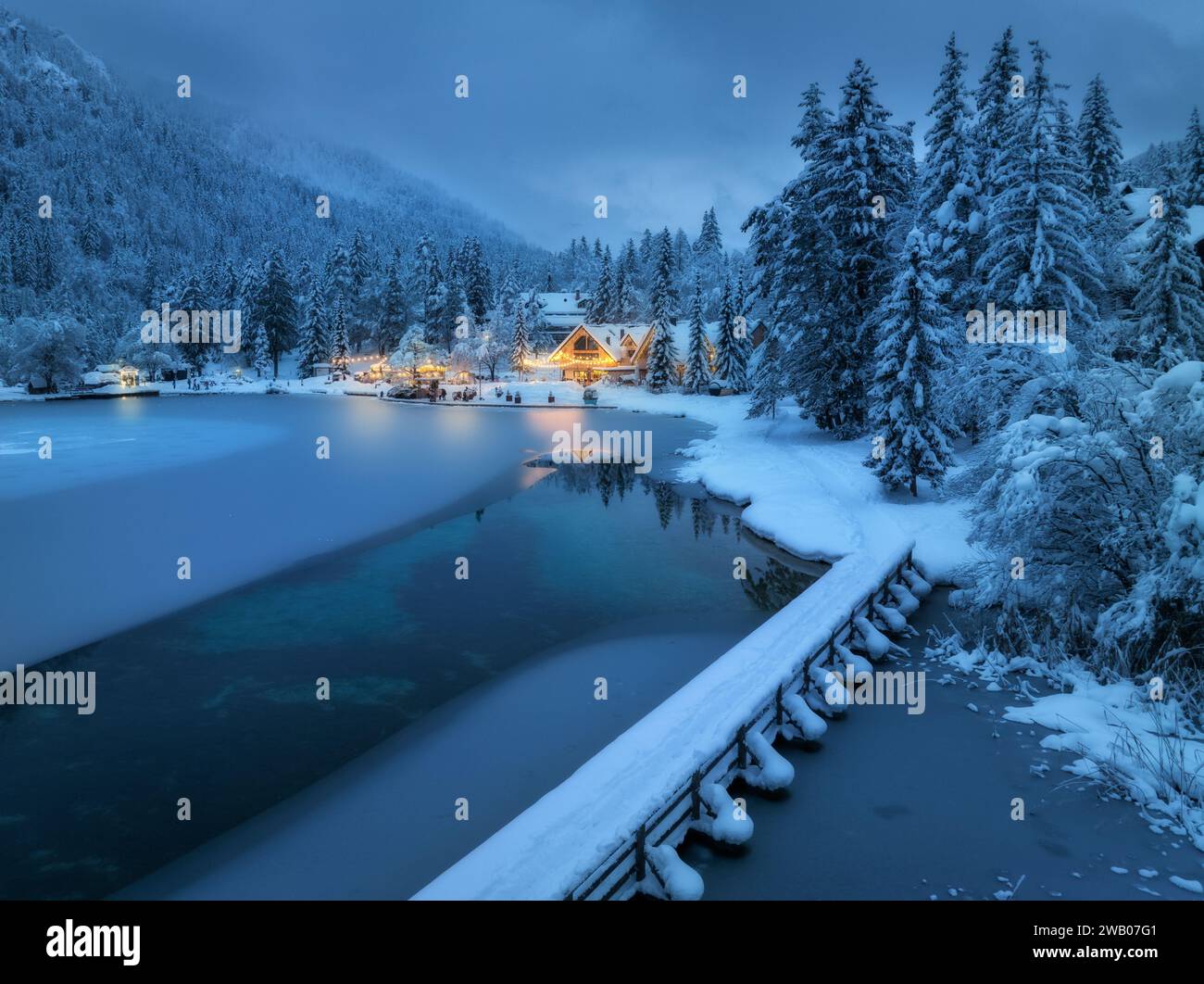 Aerial view of snowy village, trees, lake, street lights at night Stock ...
