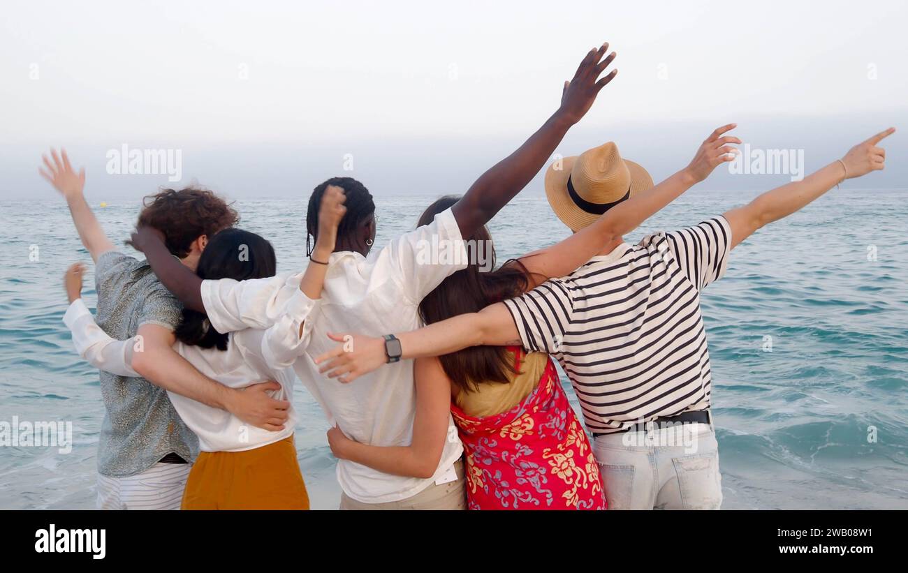 Group of diverse young friends standing back to back hugging looking at ...