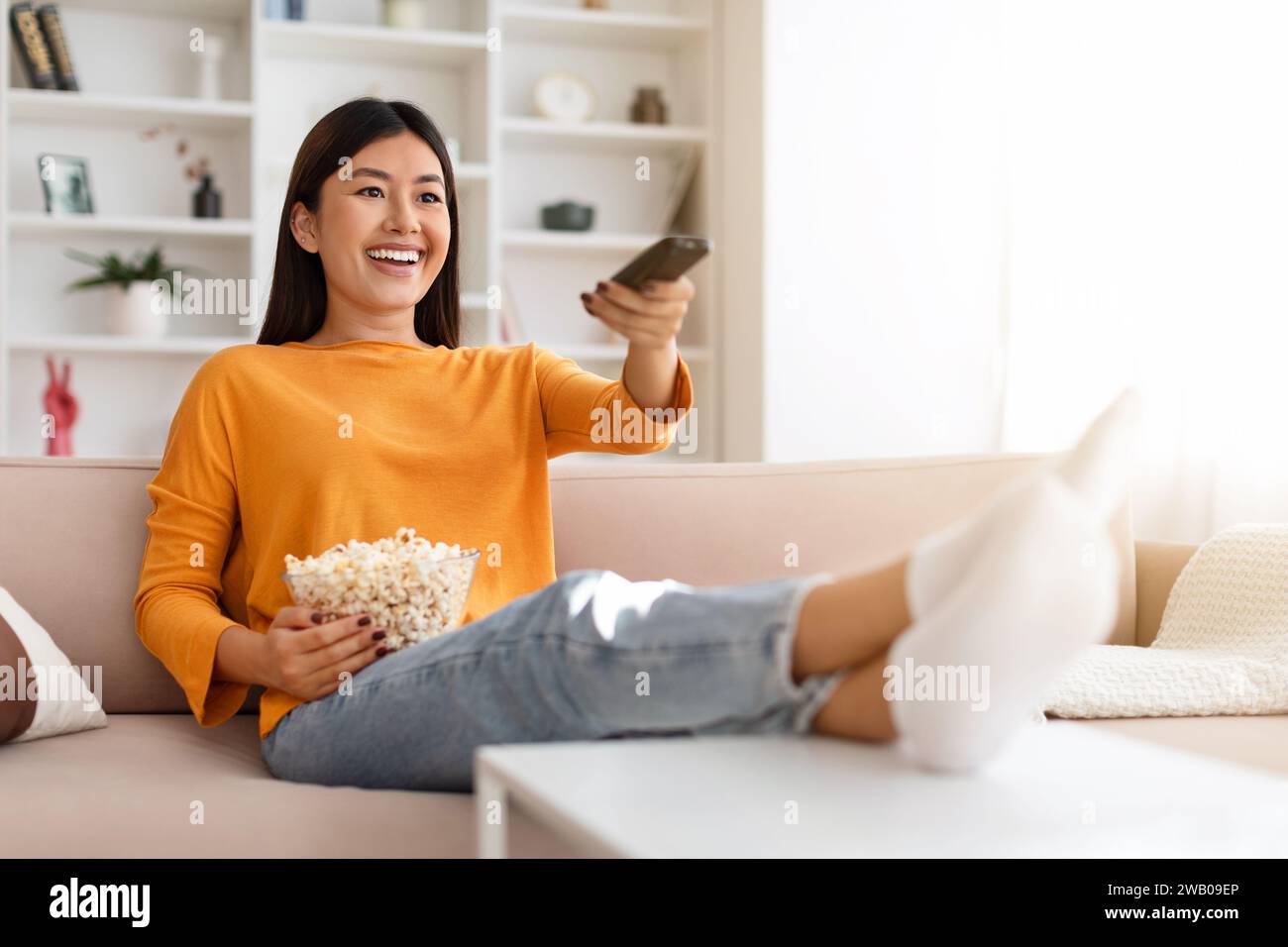 Relaxed asian woman spending free time at home, watching TV Stock Photo