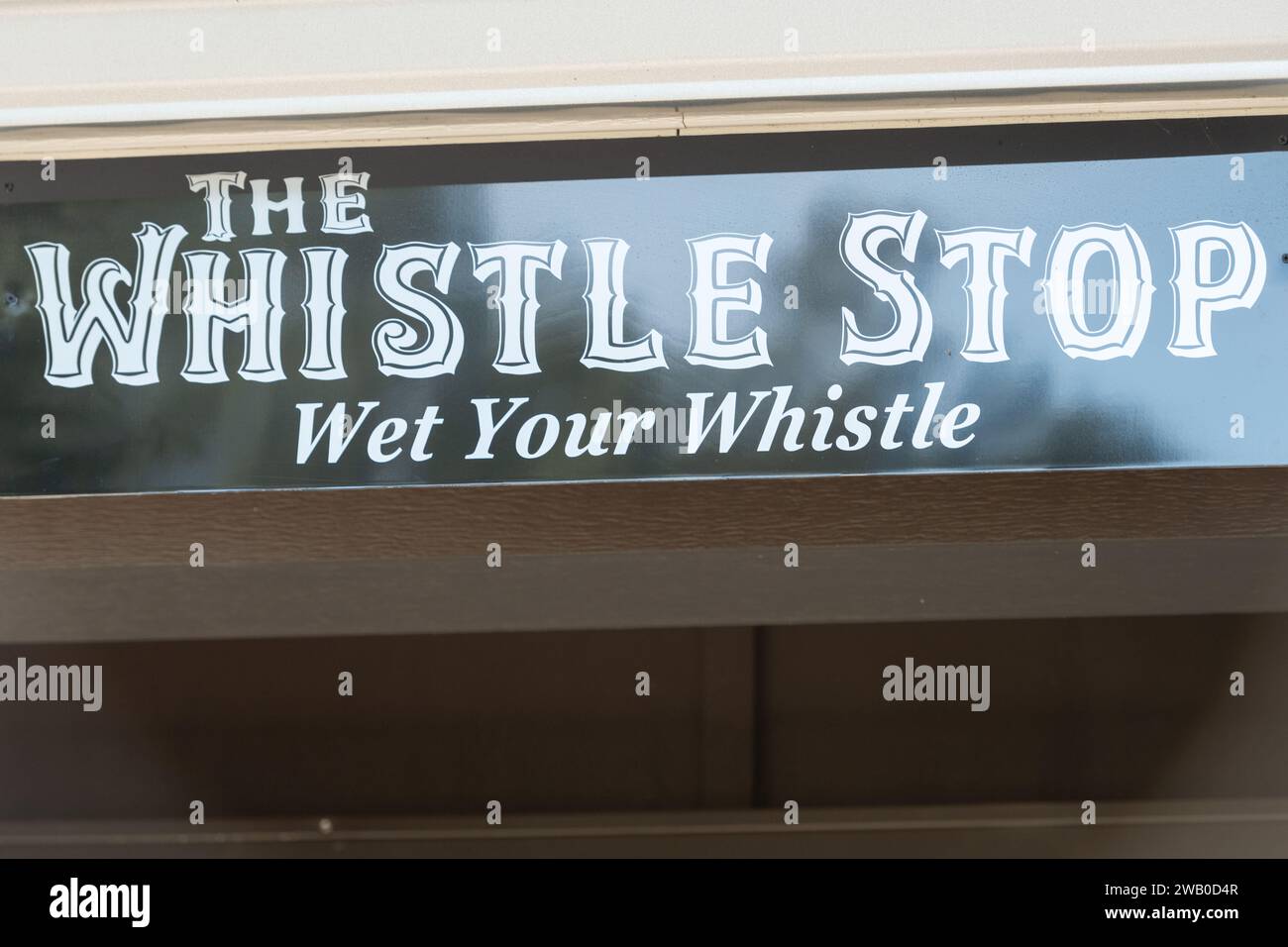 The exterior of a club with a sign over the door. The black banner has white lettering with The