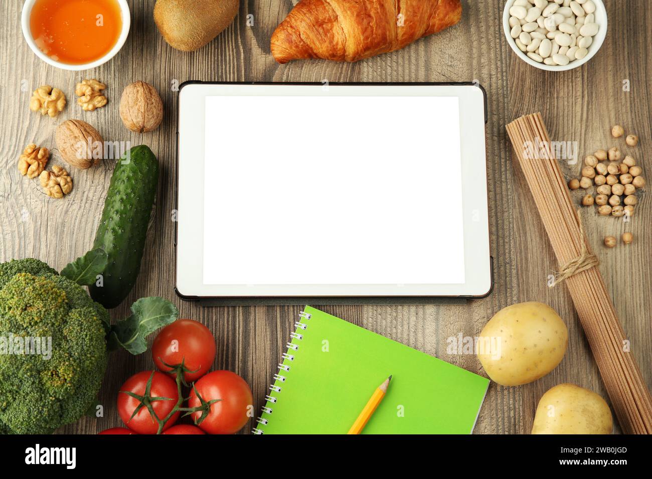 Glycemic index. Tablet with blank screen, different products and notebook on wooden table, flat lay Stock Photo