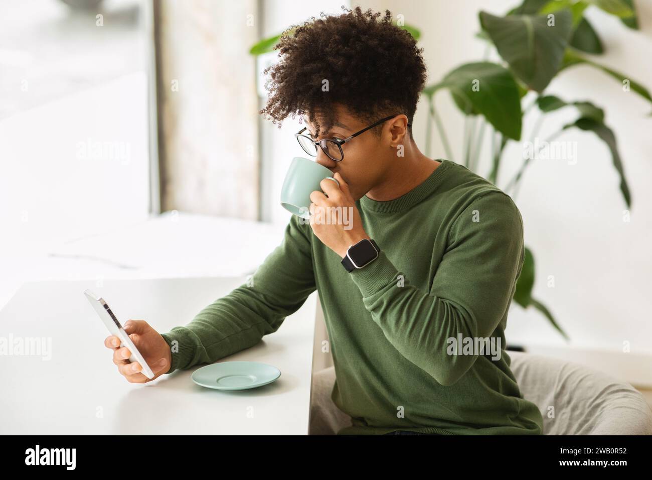 Relaxed millennial black man drinking coffee at cafe Stock Photo