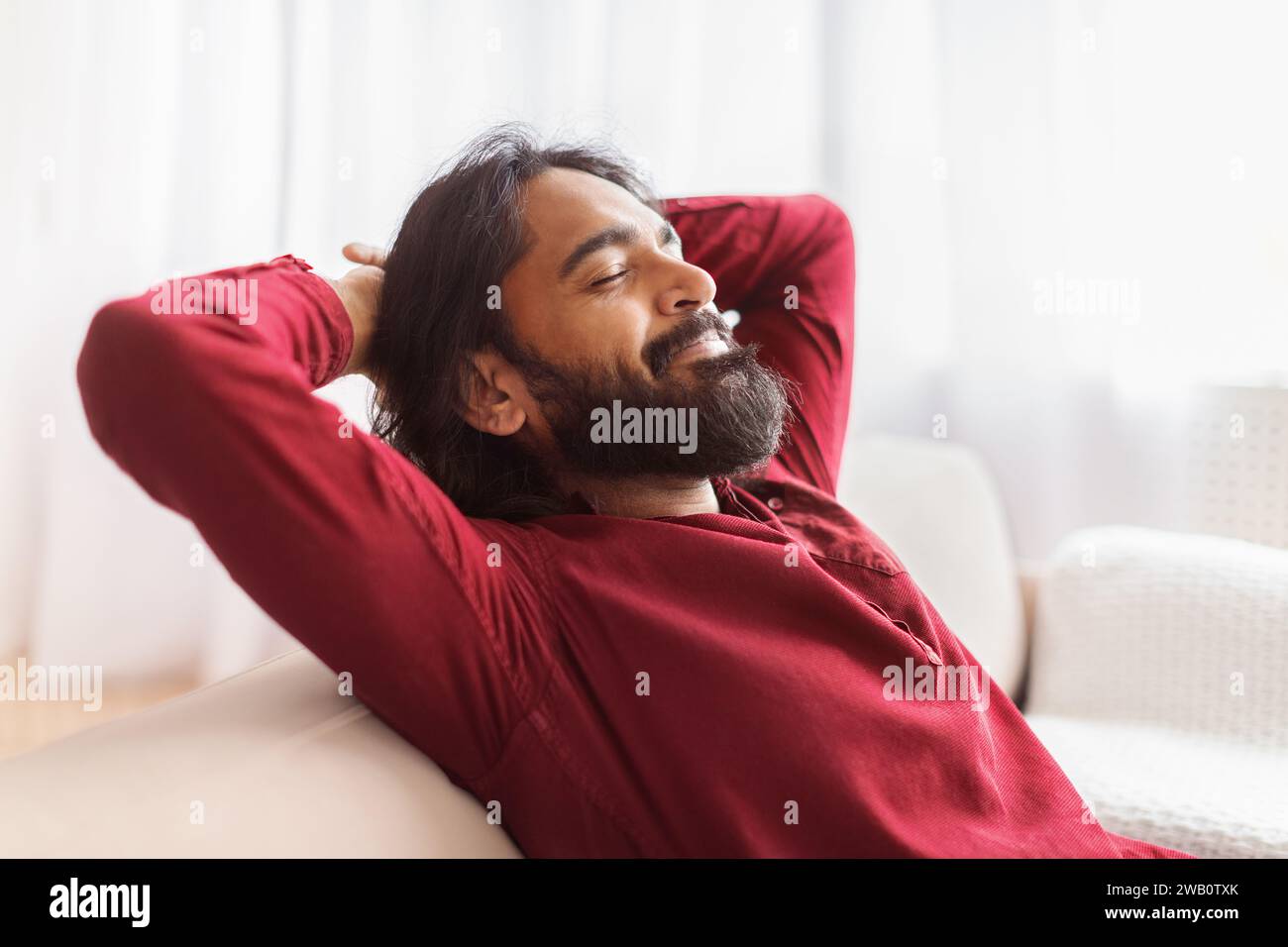 Relaxed millennial eastern man resting on couch at home Stock Photo