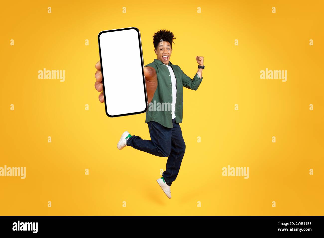 Joyful young black guy jumping with phone in his hand Stock Photo - Alamy