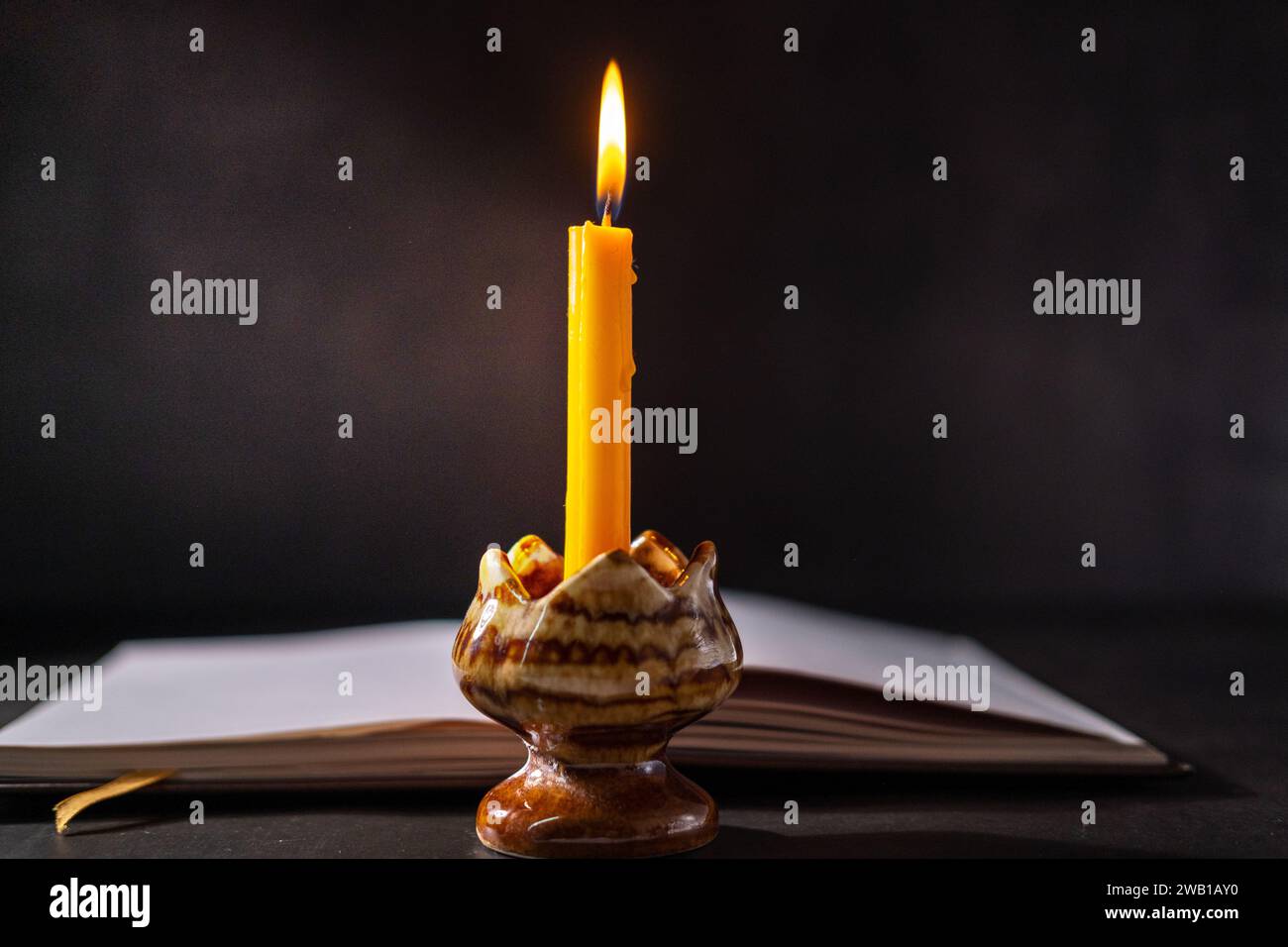 Yellow candlestick gives light while reading, black background Stock