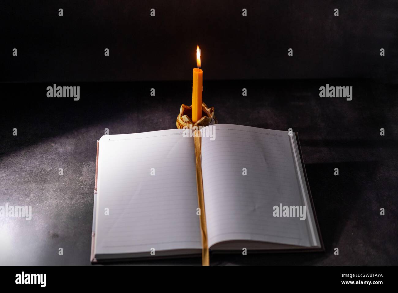 Yellow candlestick gives light while reading, black background Stock