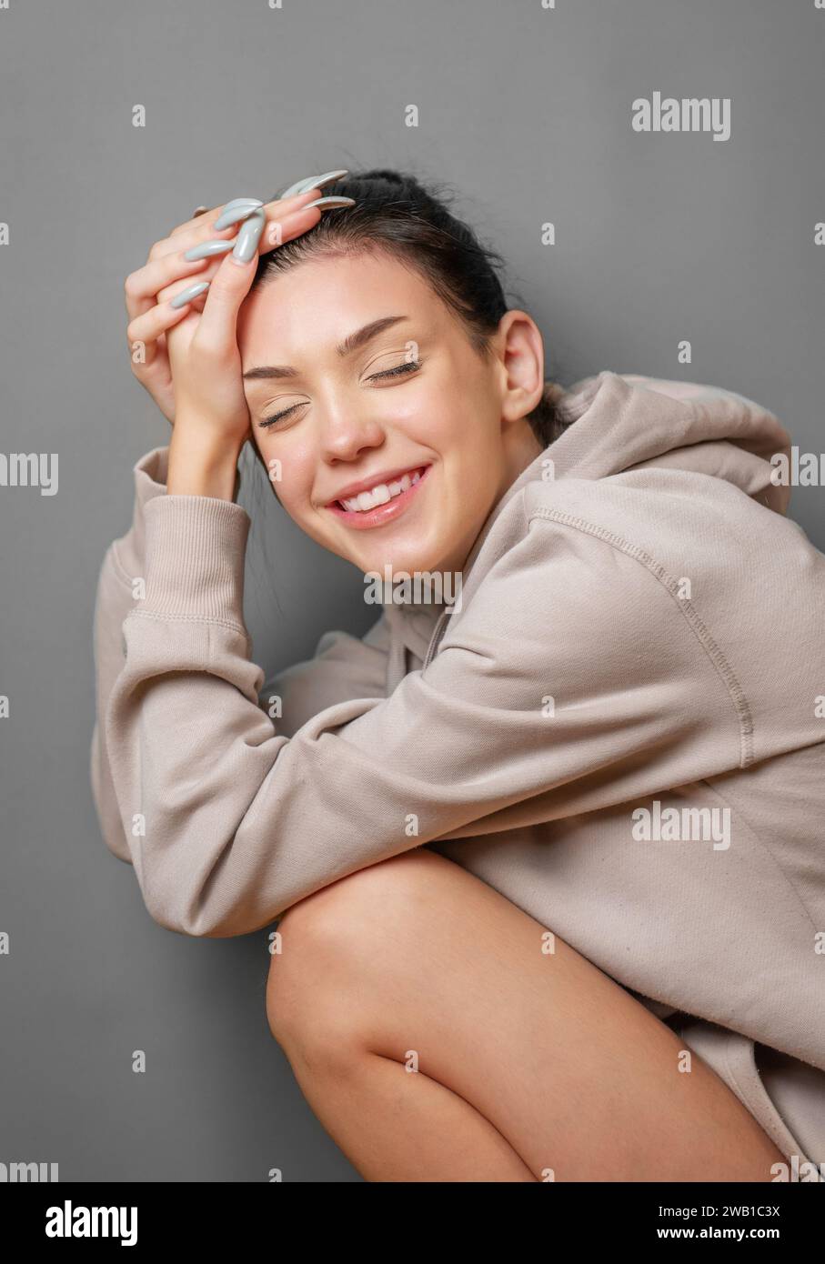 Portrait of a young pretty smoling girl in a  hoodie Stock Photo