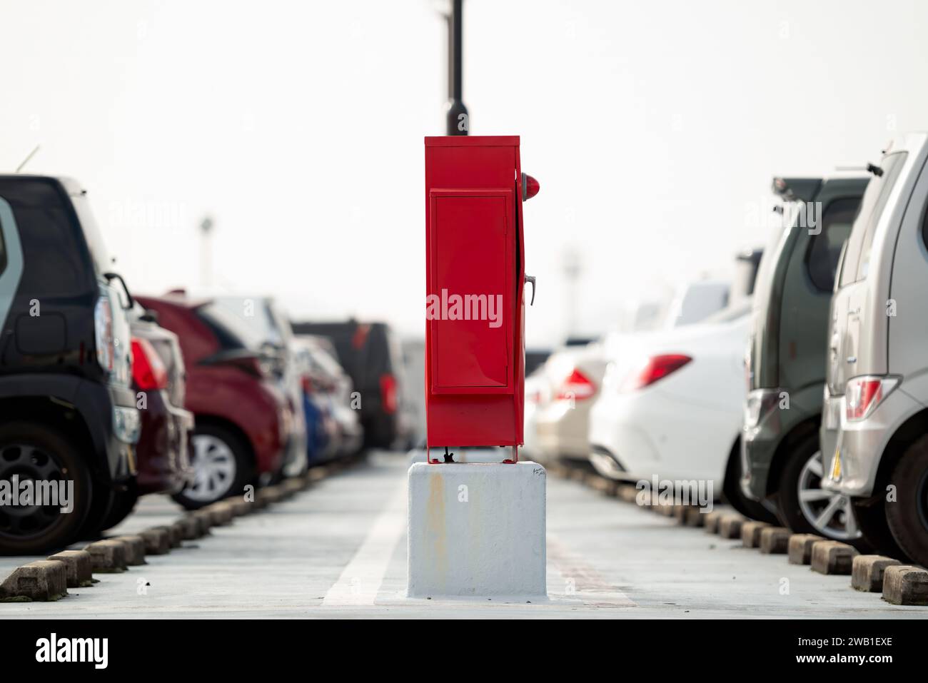 Fire extinguisher and hydrant box at the center of a building's parking lot. Stock Photo
