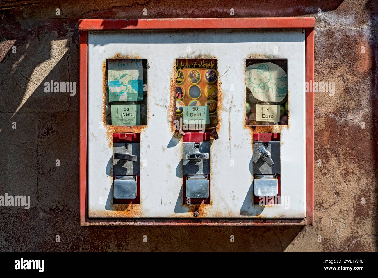 Old rusty triple chewing gum machine on a wall, vending machine for