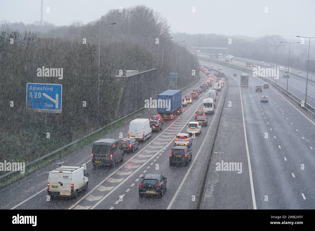 Vehicles drive through a snow shower on the M20 motorway near Maidstone in Kent. Sleet and snow showers have been forecast for parts of the country on Monday as some regions are still trying to grapple with flooding following intense rainfall. Picture date: Monday January 8, 2024. Stock Photo