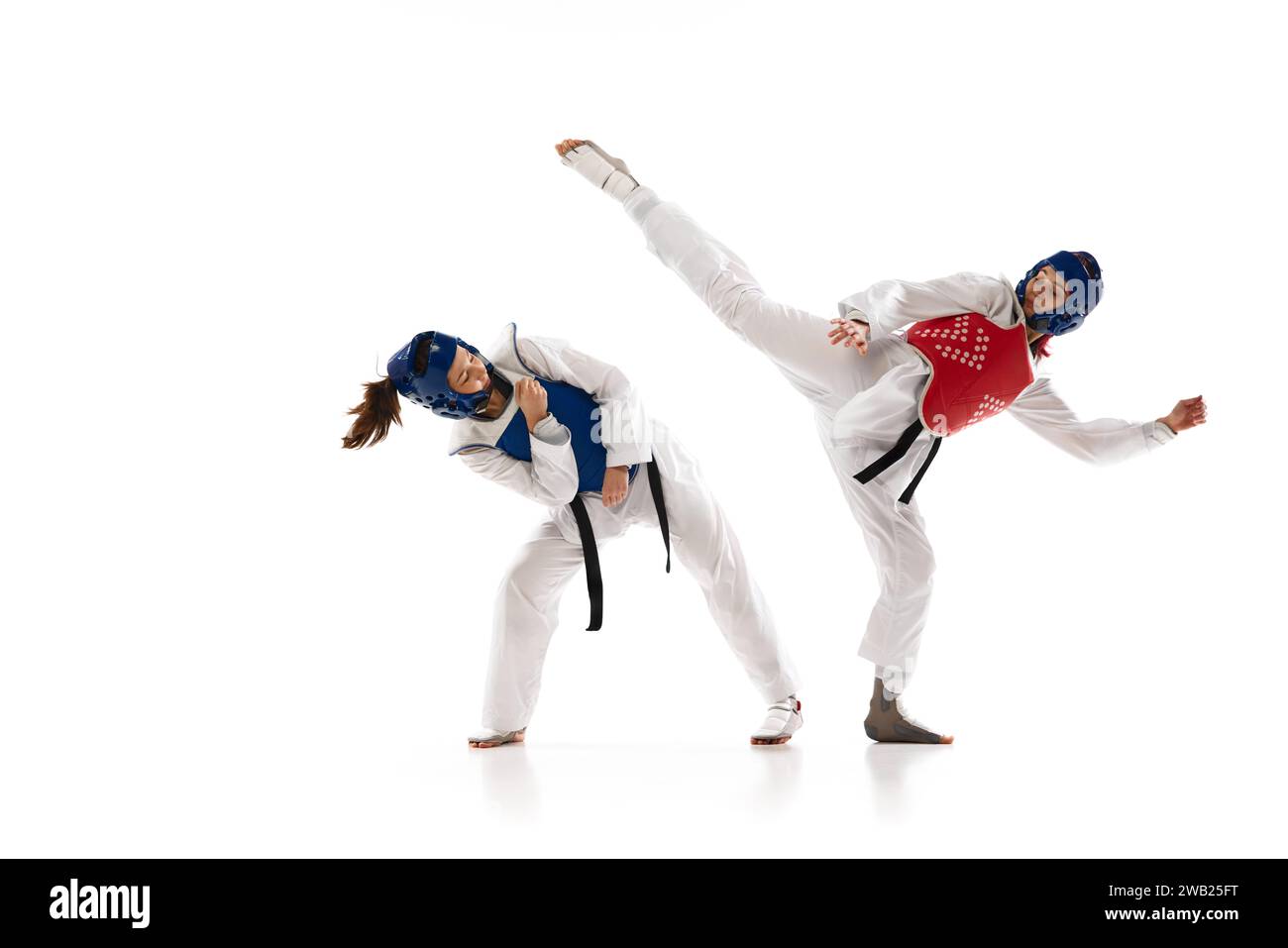 Korean martial art. Asian sport wrestling, fighting battle. Two young girl in white dobok, kimono practicing taekwondo isolated over white background Stock Photo
