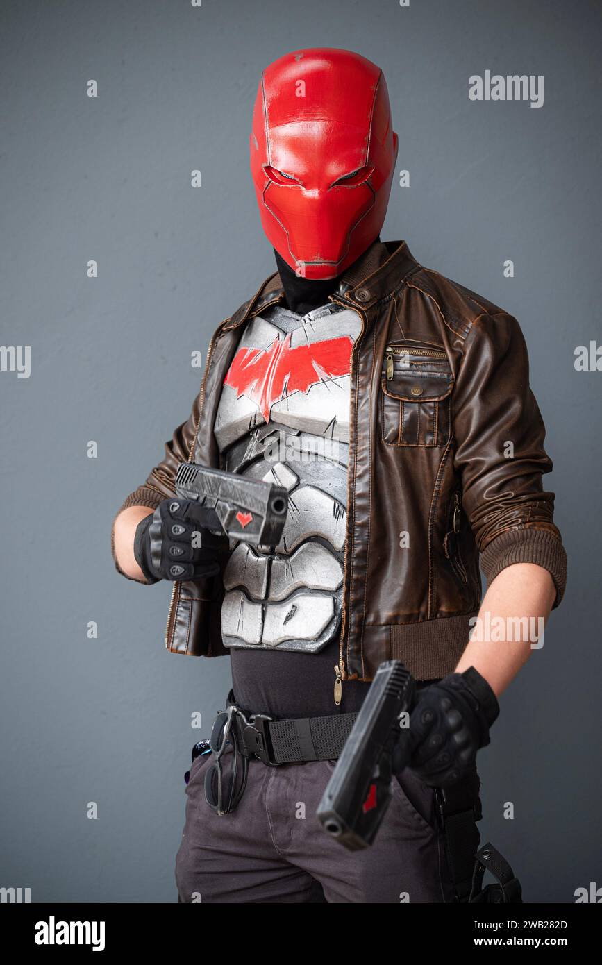 A male cosplayer in a costume with a red helmet, leather jacket, and