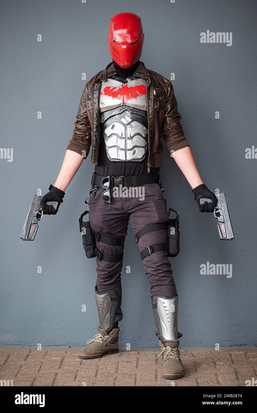 A male cosplayer in a costume with a red helmet, leather jacket, and