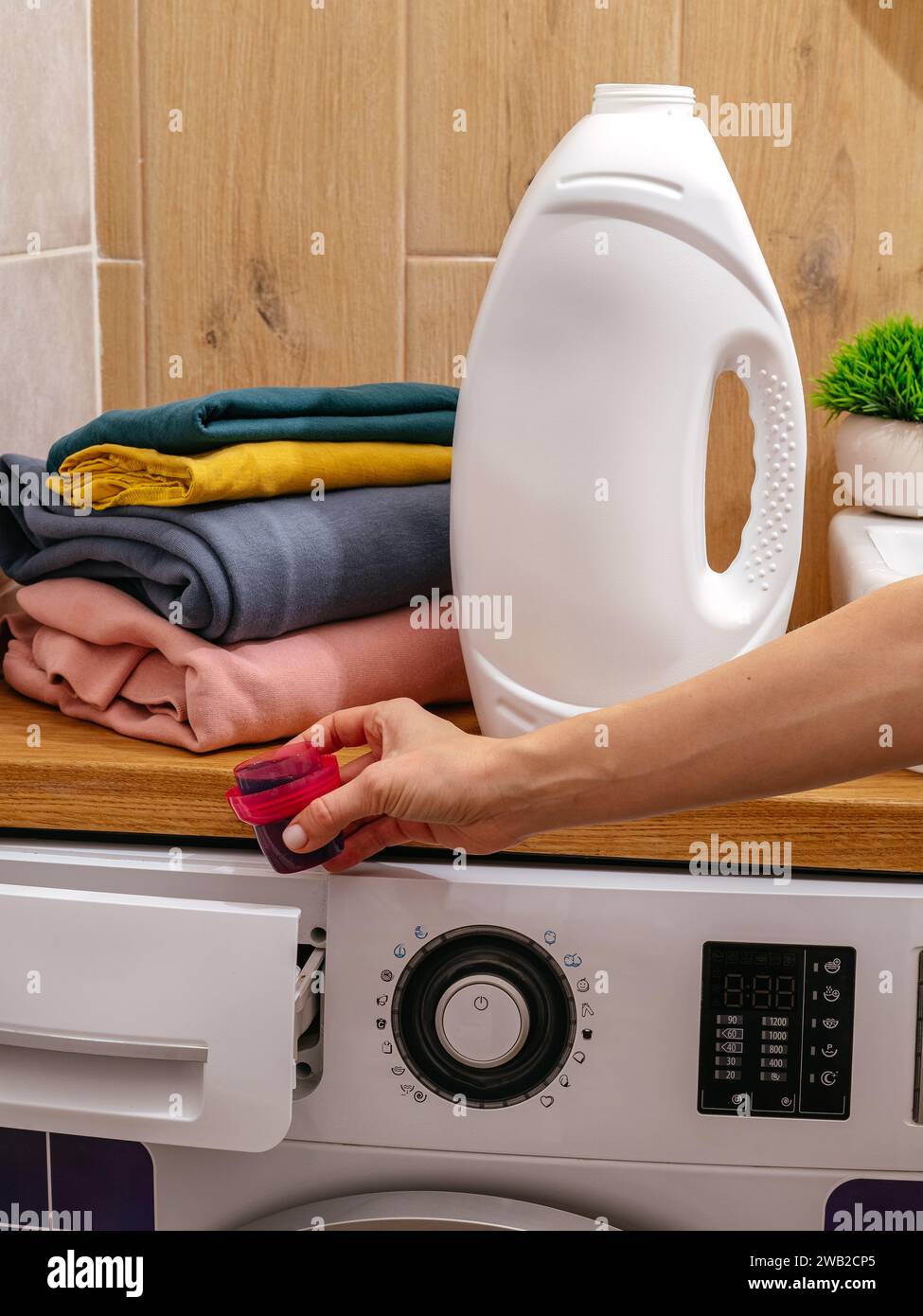 the girl pours the washing gel into the washing machine Stock Photo
