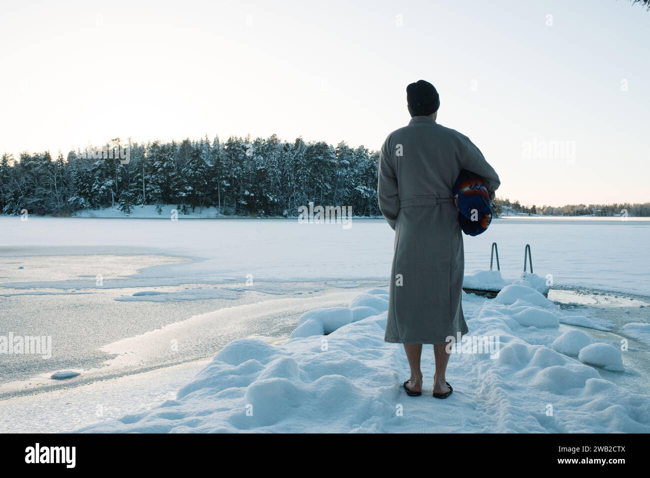Man standing in a robe ready to go cold water swimming Stock Photo