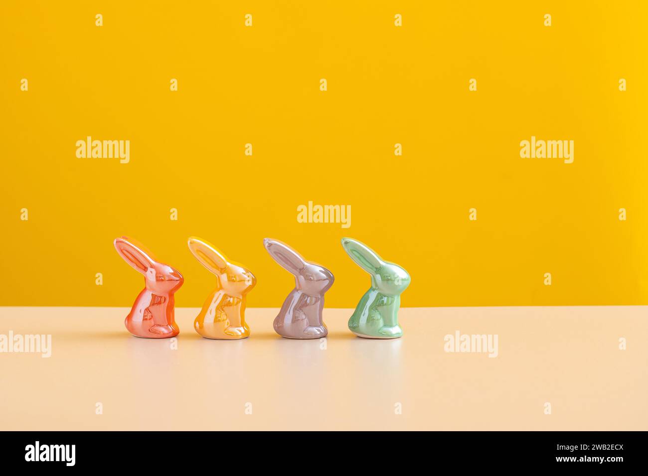 easter concept backdrop. Cheerful Ceramic Bunnies on Yellow. Stock Photo