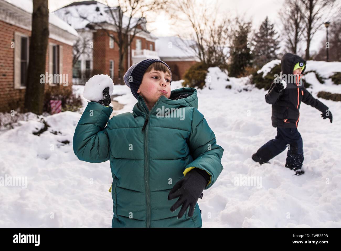 Boys in snow gear get ready to throw snowballs in yard Stock Photo