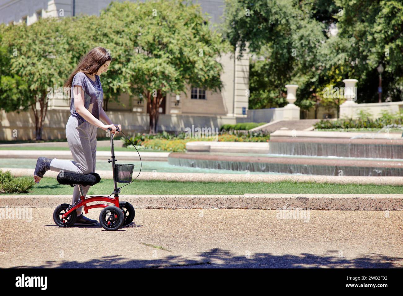 Young Woman uses Scooter to Help Get Around With Broken Leg Stock Photo