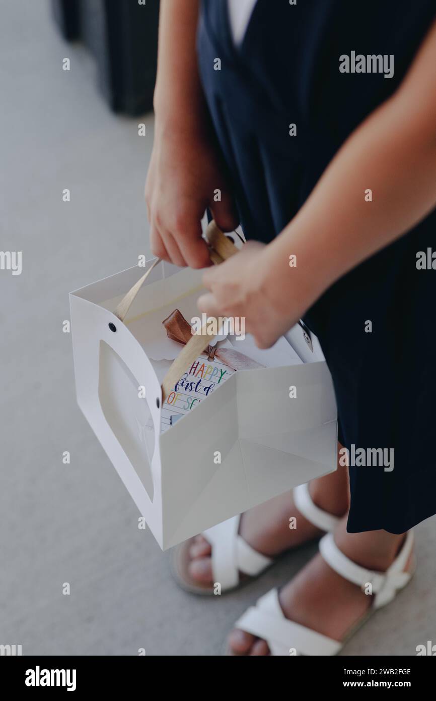 Girl student holding a white gift bag with a present inside Stock Photo