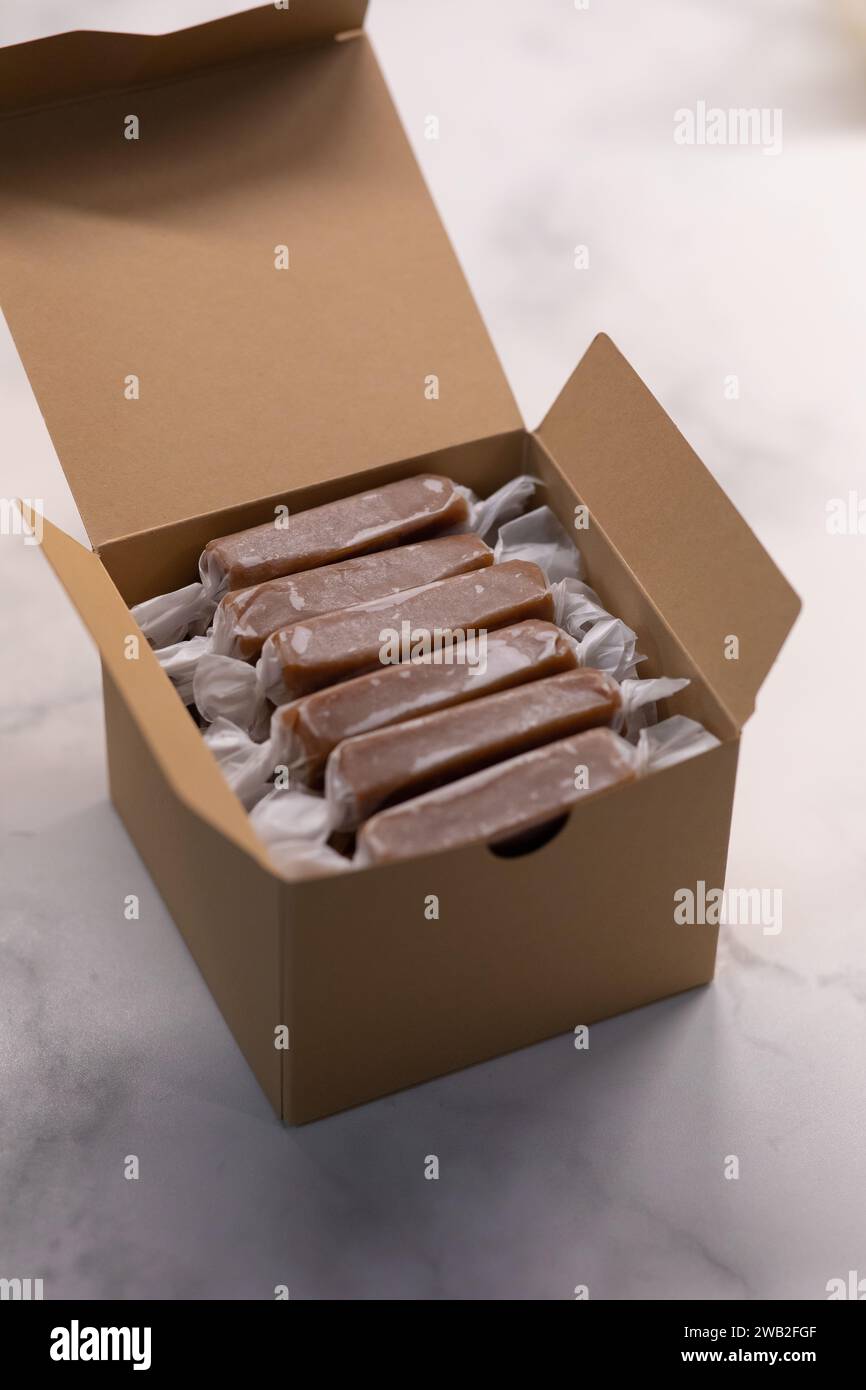Individually wrapped caramel candy in a Kraft box on a white table Stock Photo