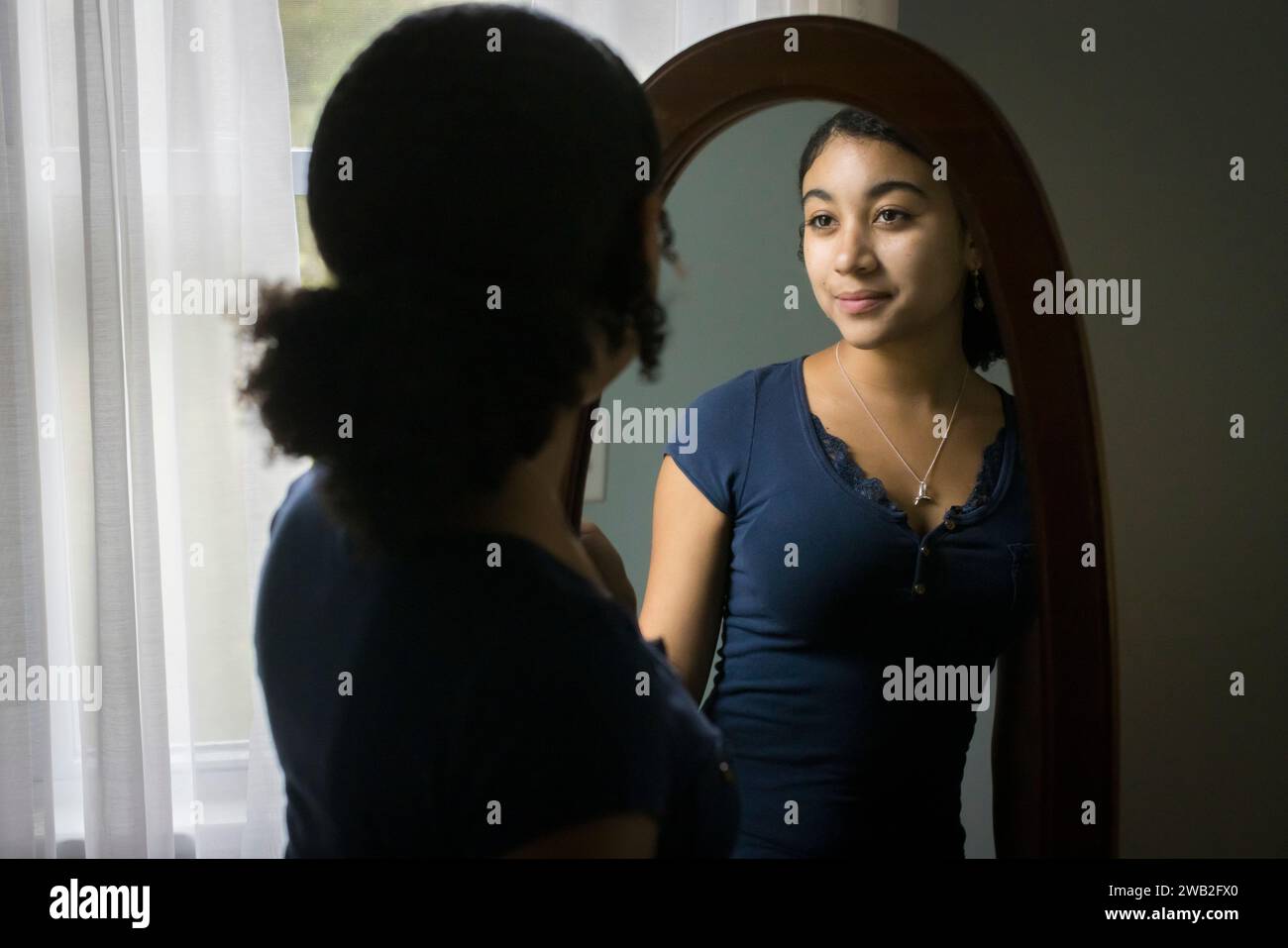 Biracial teen girl looks at hersef in the mirror Stock Photo