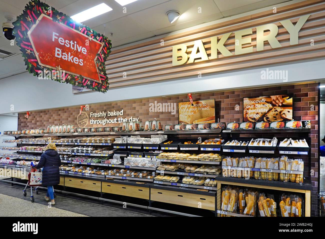 Bakery bread food department Tesco Extra supermarket interior view shopping aisle Festive Bakes sign customer self service display shelving England UK Stock Photo