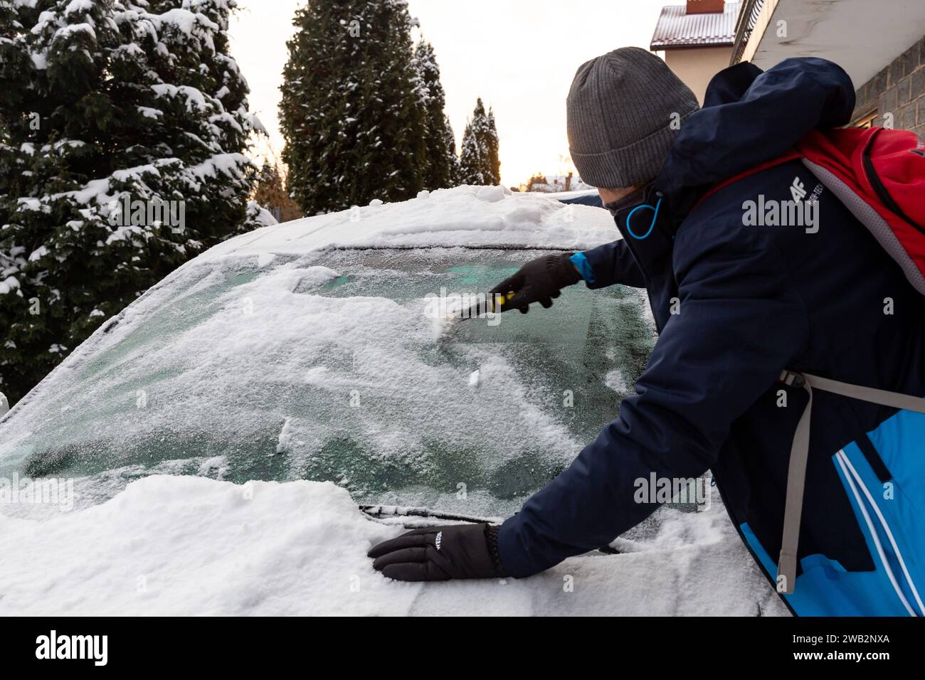 A man romeves ice of his car as the temperatures dropped and  snow fell in the night in Krakow, Poland on January 8, 2024. Stock Photo
