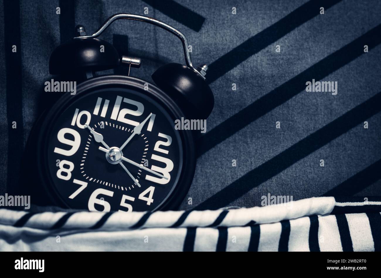 Black alarm clock on the bed. Time to sleep Stock Photo