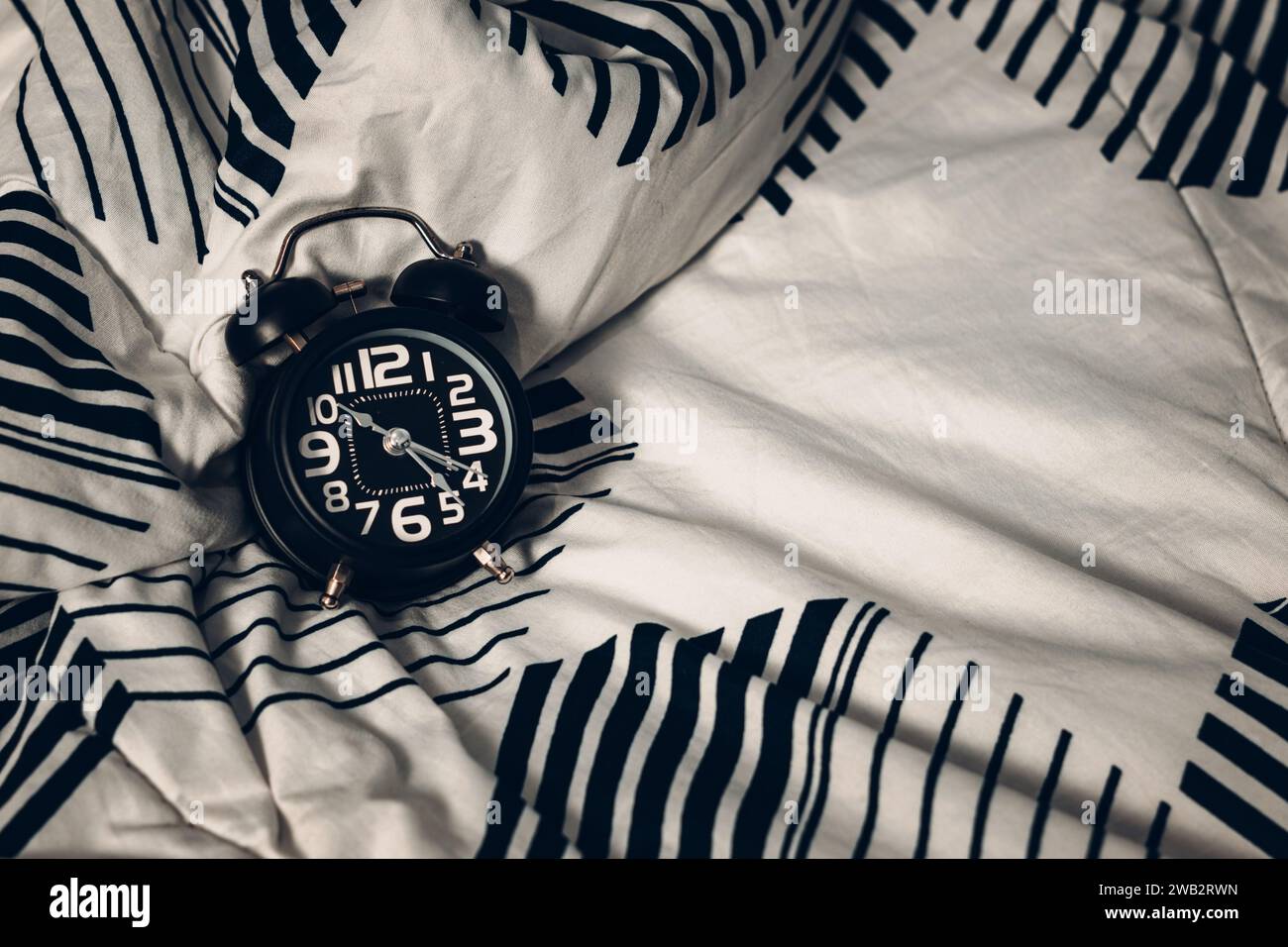 Black alarm clock on the bed. Time to sleep Stock Photo