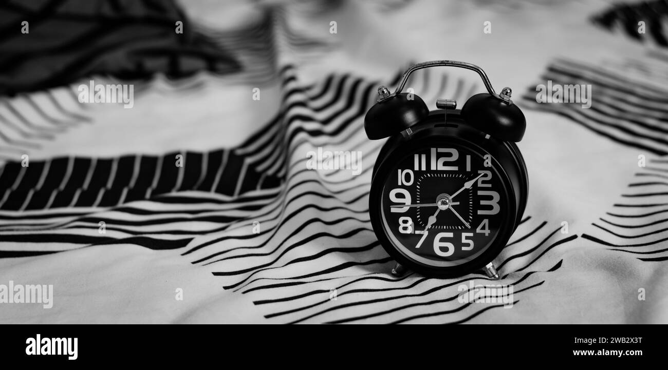 Black alarm clock on bed. Time to wake up Stock Photo Alamy