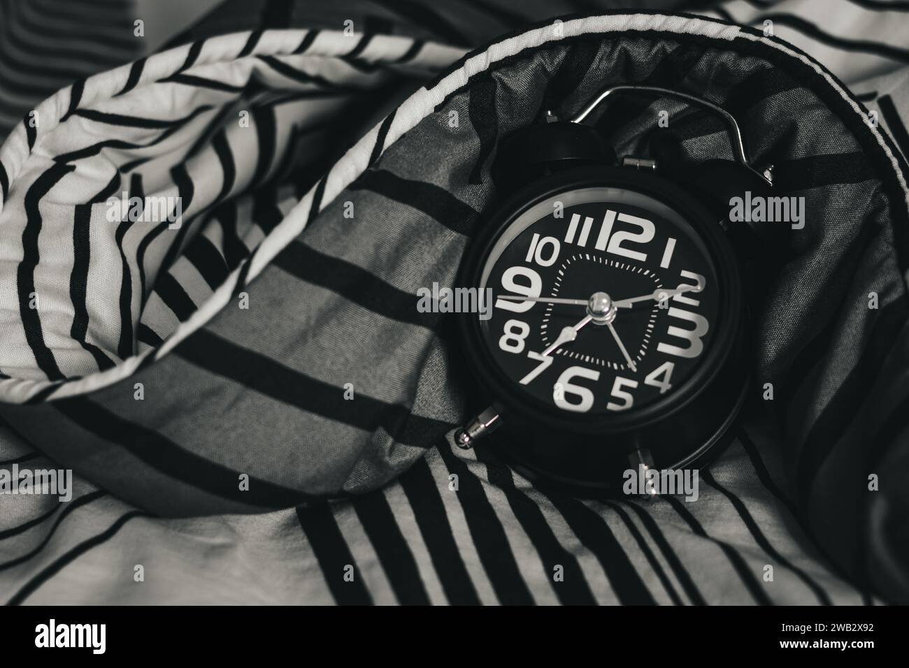 Black alarm clock on bed. Time to wake up Stock Photo